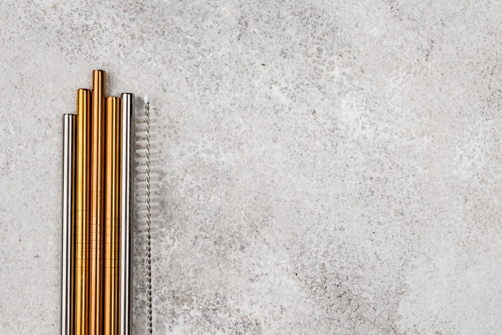 Top view of brass rectangular tubes arranged like stainless steel reusable straws on a plain background with empty copy space, highlighting their sleek and decorative appeal.